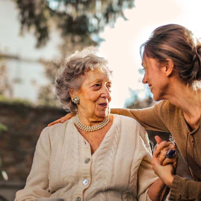 Dos mujeres conversando y sonriendo, una acompaña a la otra