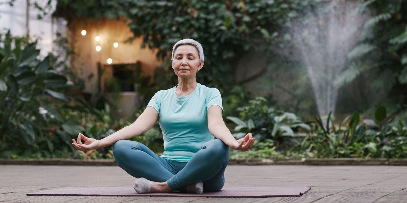 Mujer meditando en un jardín, imagen ilustrativa de bienestar